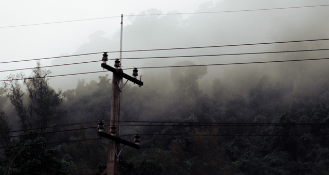 A picture of a powerline in the hills with fog